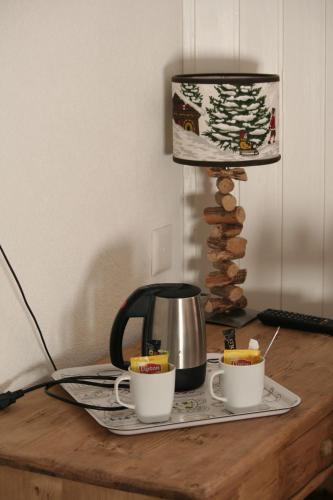 a tea kettle and two cups on a table at Hotel de la Lande in Le Brassus