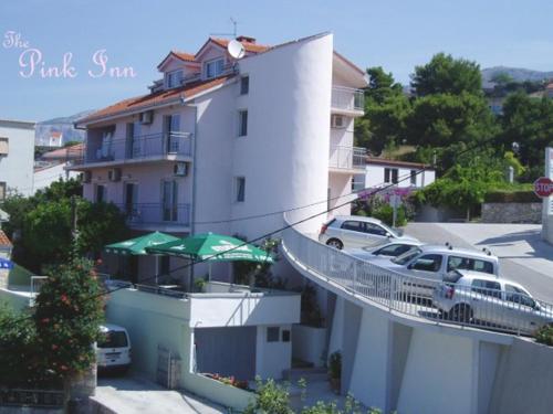 un bâtiment blanc avec une rampe menant à un parking dans l'établissement Pink Inn, à Podstrana