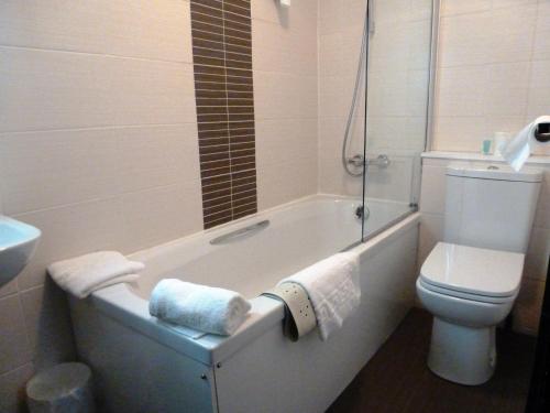 a bathroom with a tub and a toilet and a sink at The Popinjay Hotel in Larkhall