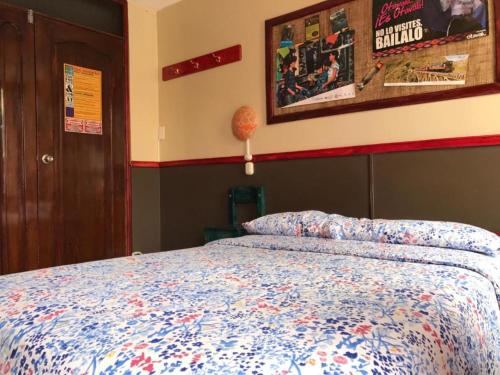 a bedroom with a bed with a blue comforter at Flying Donkey in Otavalo
