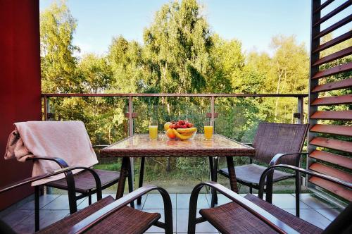 a table with a bowl of fruit on a balcony at SOPHIE APARTMENT Polanki in Kołobrzeg