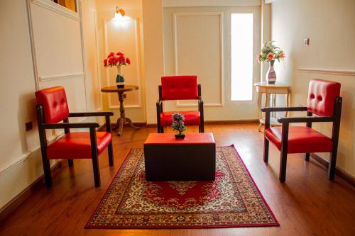 a living room with red chairs and a table and a rug at Residencial Velia & Victoria in Cochabamba