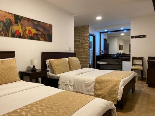 um quarto de hotel com duas camas e uma casa de banho em Casa Hotel Las Orquideas em Circasia