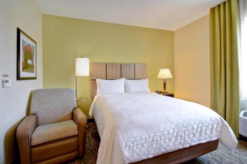 a hotel room with a bed and a chair at Candlewood Suites St Clairsville Wheeling Area, an IHG Hotel in Saint Clairsville