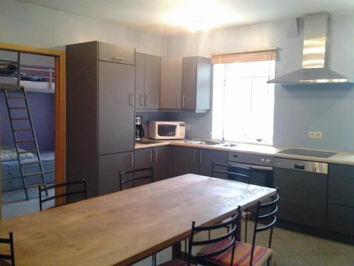 cocina con mesa de madera y sillas y cocina con nevera en Gîte Le Randonneur, en Daverdisse