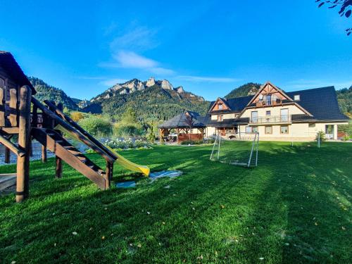 a yard with a playground with a house and mountains at Willa Magiera in Sromowce Niżne