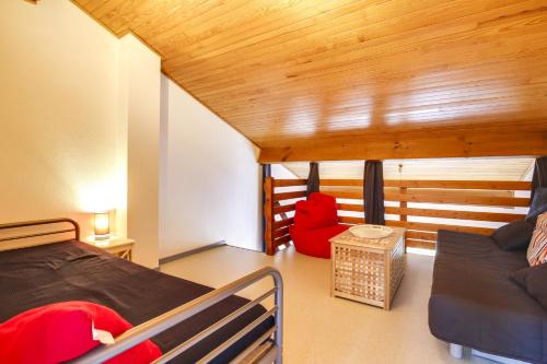 a bedroom with a bed and a couch in a room at Appartement en duplex 2* Résidence Les Pêcheurs in Biscarrosse