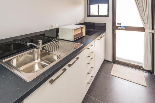 a kitchen with a sink and a microwave on a counter at Burwood Motel in Whanganui