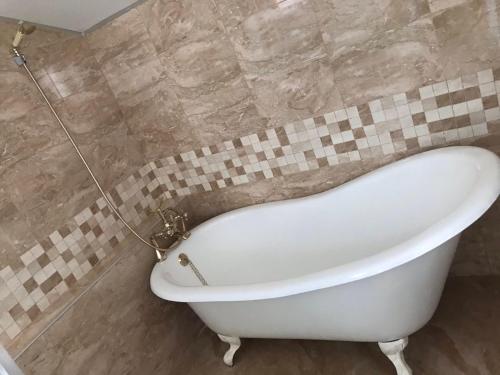 a white bath tub in a tiled bathroom at Guest House Kalina in Sapareva Banya