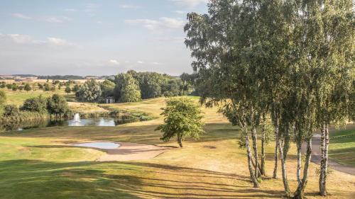 a view of a golf course with a pond and trees at Lydinge Resort in Hyllinge