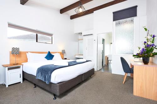 um quarto com uma cama king-size, uma secretária e uma cadeira. em Cobblestone Court Motel - Wenzel Motels em Tauranga