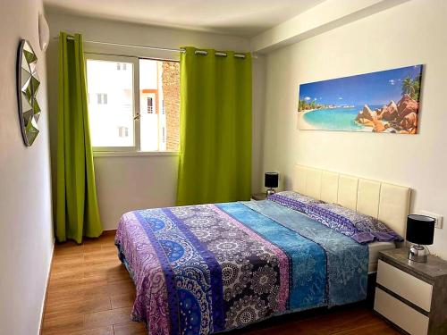 1 dormitorio con 1 cama y una ventana con cortinas verdes en Cristianos, en Los Cristianos