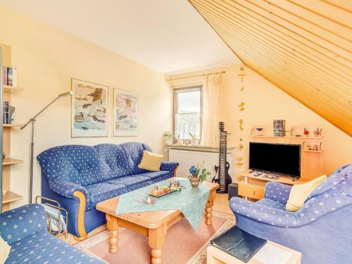 een woonkamer met blauwe banken en een tv bij Cozy Apartment in P hlde With Sauna in Herzberg am Harz