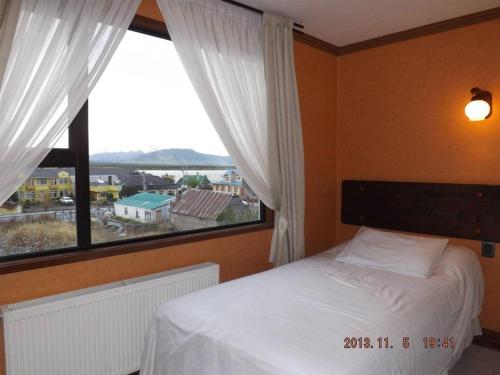 a bedroom with a bed and a large window at Hotel Saltos del Paine in Puerto Natales