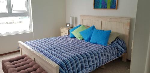 1 dormitorio con 1 cama con almohadas azules y verdes en Departamento Papudo Laguna 120, en Papudo