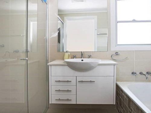 La salle de bains blanche est pourvue d'un lavabo et d'une douche. dans l'établissement Surf Mist, à Gerroa