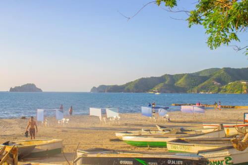 a beach with boats and chairs and people on it at Hotel Rodadero Inn By GEH Suites in Santa Marta
