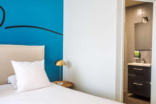 a bedroom with a white bed and a blue wall at Sure Hotel by Best Western Argentan in Argentan