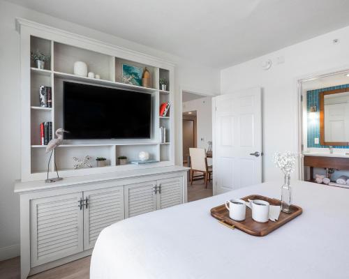 a white bedroom with a flat screen tv on top of a bed at Compass Hotel by Margaritaville Anna Maria Sound in Bradenton