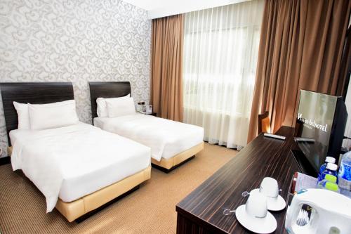 a hotel room with two beds and a table at Swiss-Belhotel Kendari in Kendari