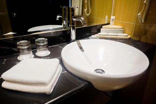 a bathroom sink with towels on a black counter at Swiss-Belhotel Kendari in Kendari