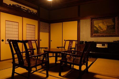 a room with chairs and a table and a painting at Guesthouse SHIGI in Nakatsugawa