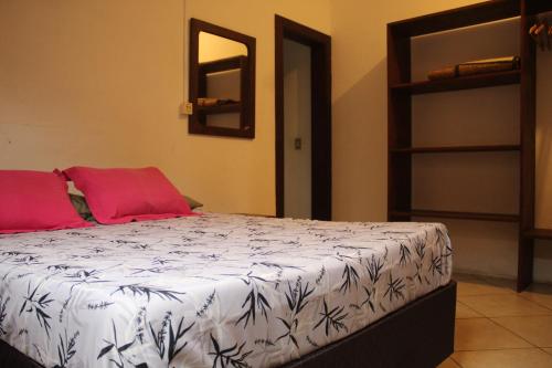 a bedroom with a bed with white sheets and red pillows at Boa Vibe Complexo Rosa Norte in Praia do Rosa