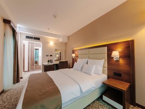 a bedroom with a large bed and a desk at Hotel New Star in Podgorica