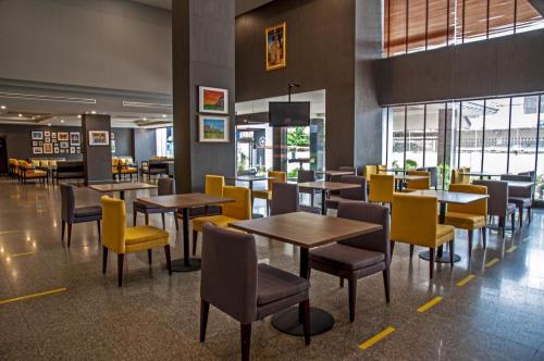 uma sala de jantar com mesas e cadeiras amarelas em Le cassia Hotel em Khon Kaen