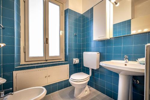 a blue tiled bathroom with a toilet and a sink at Hotel Villani in Florence
