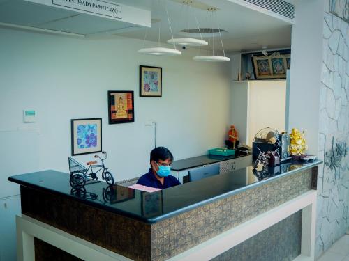 a person wearing a mask at a counter in a room at White Pearl Residency in Puducherry