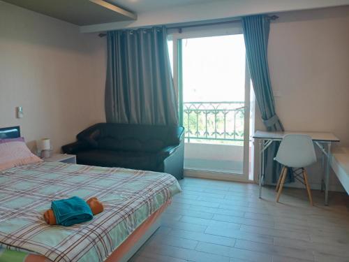 a bedroom with a bed and a chair and a window at Seven Seas Condo G619/E519 in Jomtien Beach