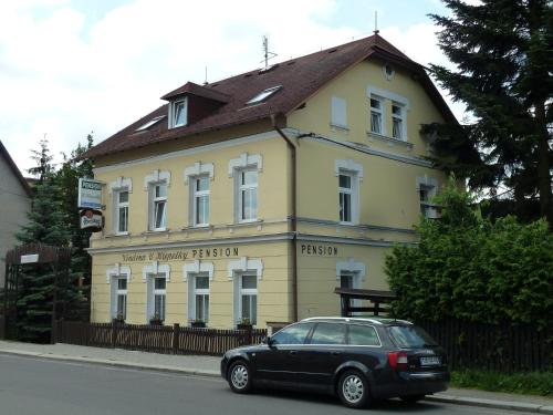 a black car parked in front of a yellow building at Penzion Holiday in Mariánské Lázně