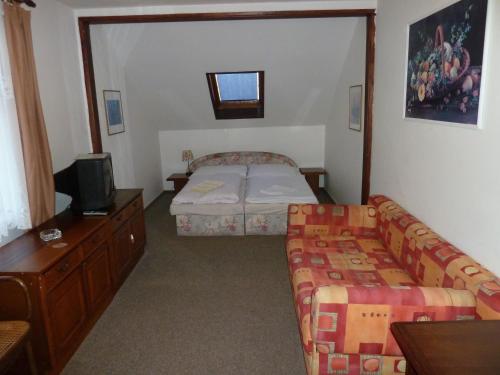 a room with two beds and a couch and a tv at Penzion Holiday in Mariánské Lázně
