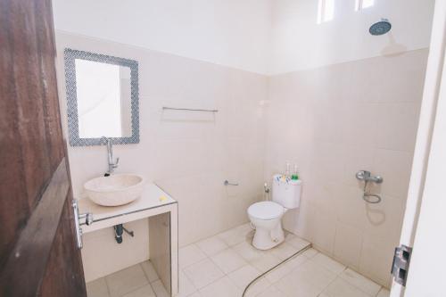 W łazience znajduje się umywalka, toaleta i lustro. w obiekcie Damar Sanjaya Uttama w mieście Amed