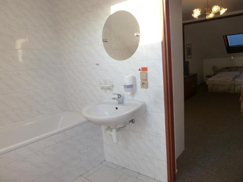 a bathroom with a sink and a tub and a mirror at Penzion Holiday in Mariánské Lázně