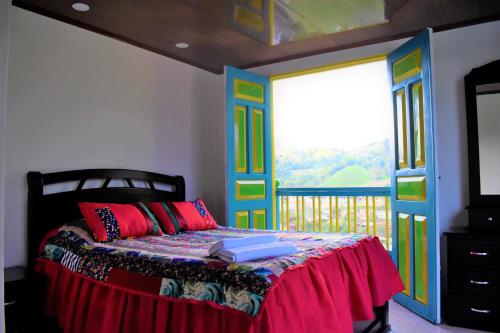 a bedroom with a bed with colorful doors and a balcony at Posada Dónde Cupeto in Salento