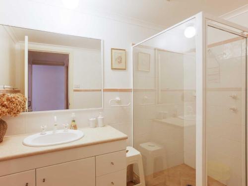 a white bathroom with a sink and a shower at Peninsula Waters 1 Aircon pool and massive outdoor area in Soldiers Point