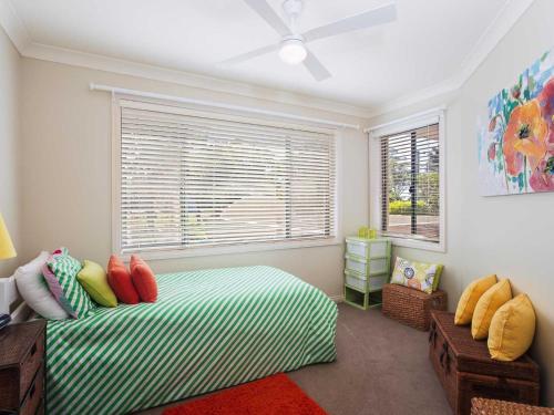 a bedroom with a green and white bed and a window at Peninsula Waters 1 Aircon pool and massive outdoor area in Soldiers Point