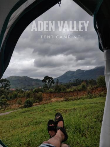 a person sitting in a tent looking out at a field at Aden Valley Resort in Kanthalloor