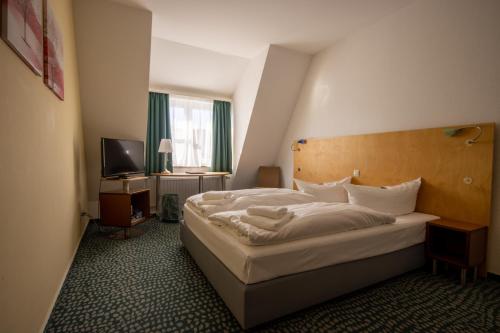 Habitación de hotel con cama y TV en Check Inn Hotel Merseburg, en Merseburgo