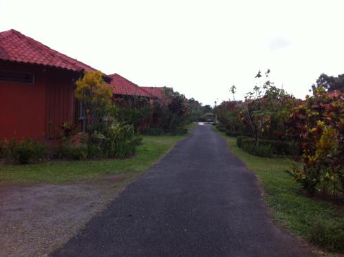 an empty road in front of a red building at Hotel Villas Vista Arenal in Fortuna
