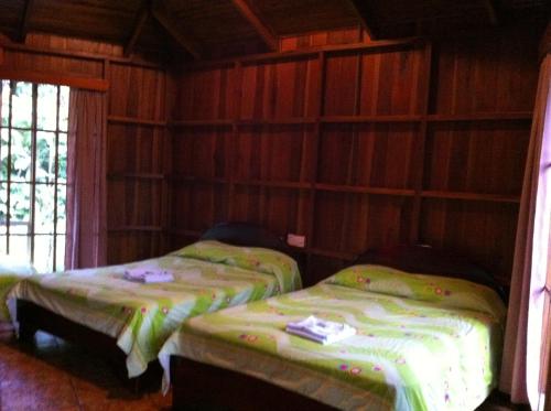 two beds in a room with wooden walls at Hotel Villas Vista Arenal in Fortuna
