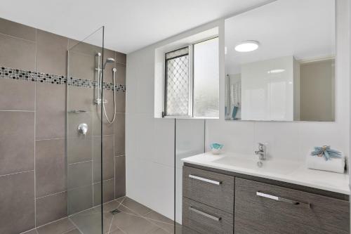 Un baño con ducha, lavabo y espejo. en Chidori Court, en Gold Coast
