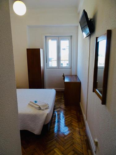 a small room with a bed and a television at Poveira Hotel in Porto