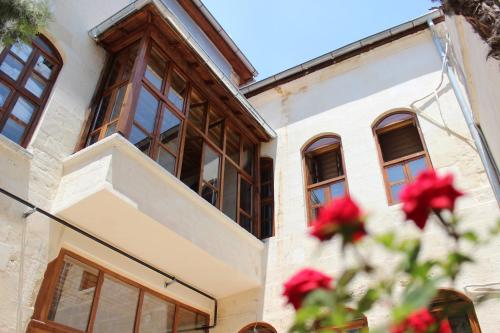 a building with windows and red flowers in the foreground at Duran Aga Konagi in Şahinbey