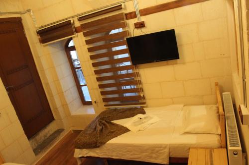 a small room with a bed and a television at Duran Aga Konagi in Şahinbey