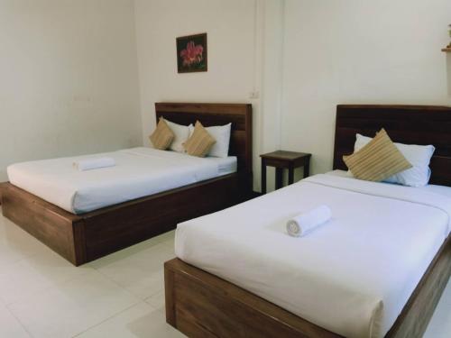 two beds in a hotel room with white sheets at Rachawadee House in Phangnga