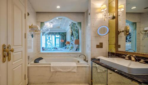 a bathroom with a tub and a sink and a mirror at Yungang Jianguo Hotel in Datong