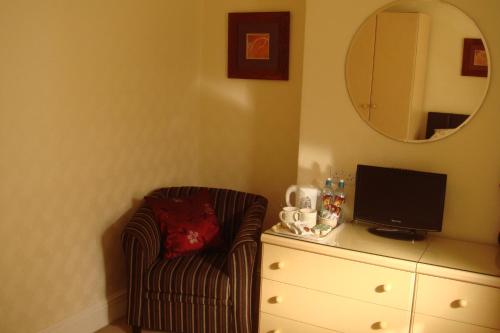 a bedroom with a chair and a dresser with a television at Wendover Guest House in Bolton